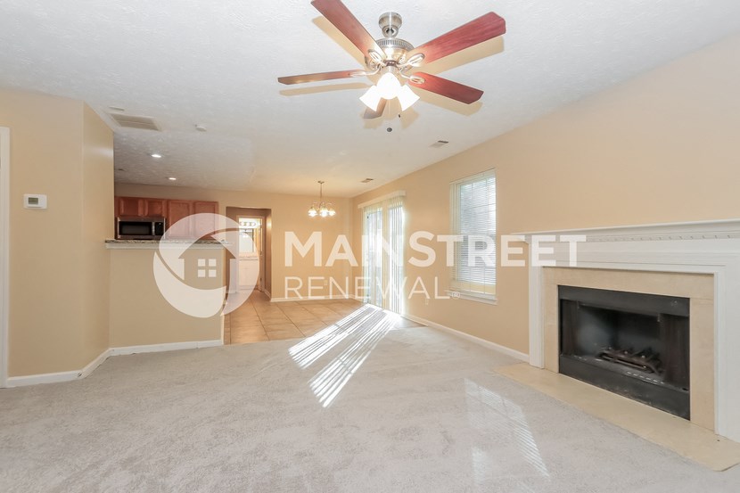 a living room with a fireplace and a ceiling fan