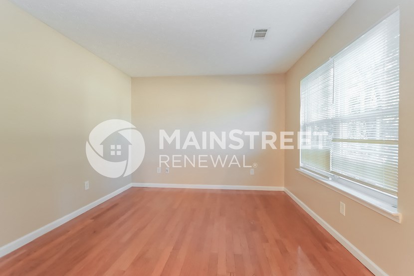 a bedroom with a wood floor and a large window