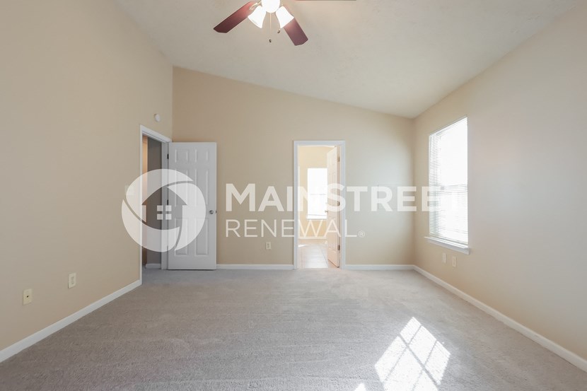 a master bedroom with a carpeted floor and a door to the bathroom