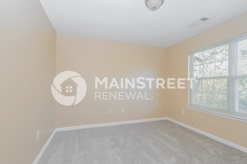 a bedroom with a carpeted floor and two windows