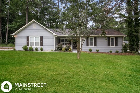 a small house with a lawn and a tree in the front