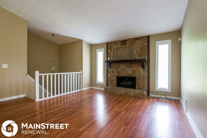 an empty living room with a fireplace and wooden floors