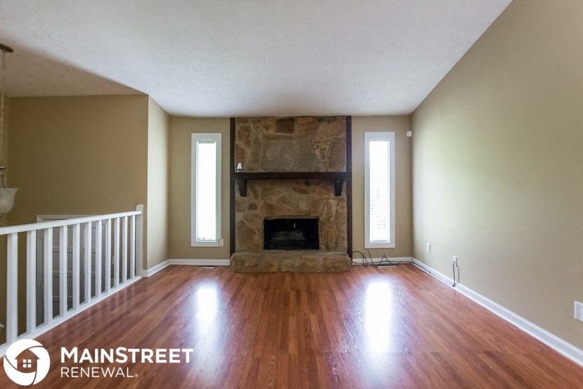 an empty living room with a fireplace and wooden floors