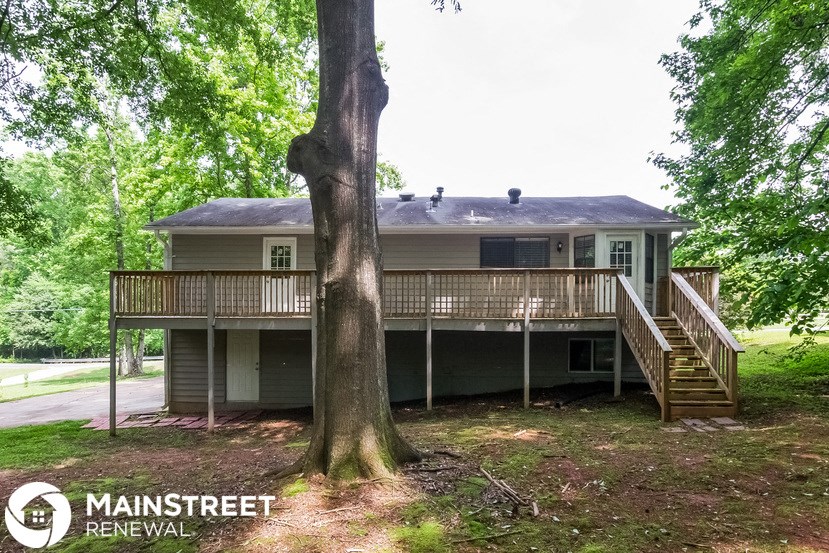 the back of a house with a deck and a tree