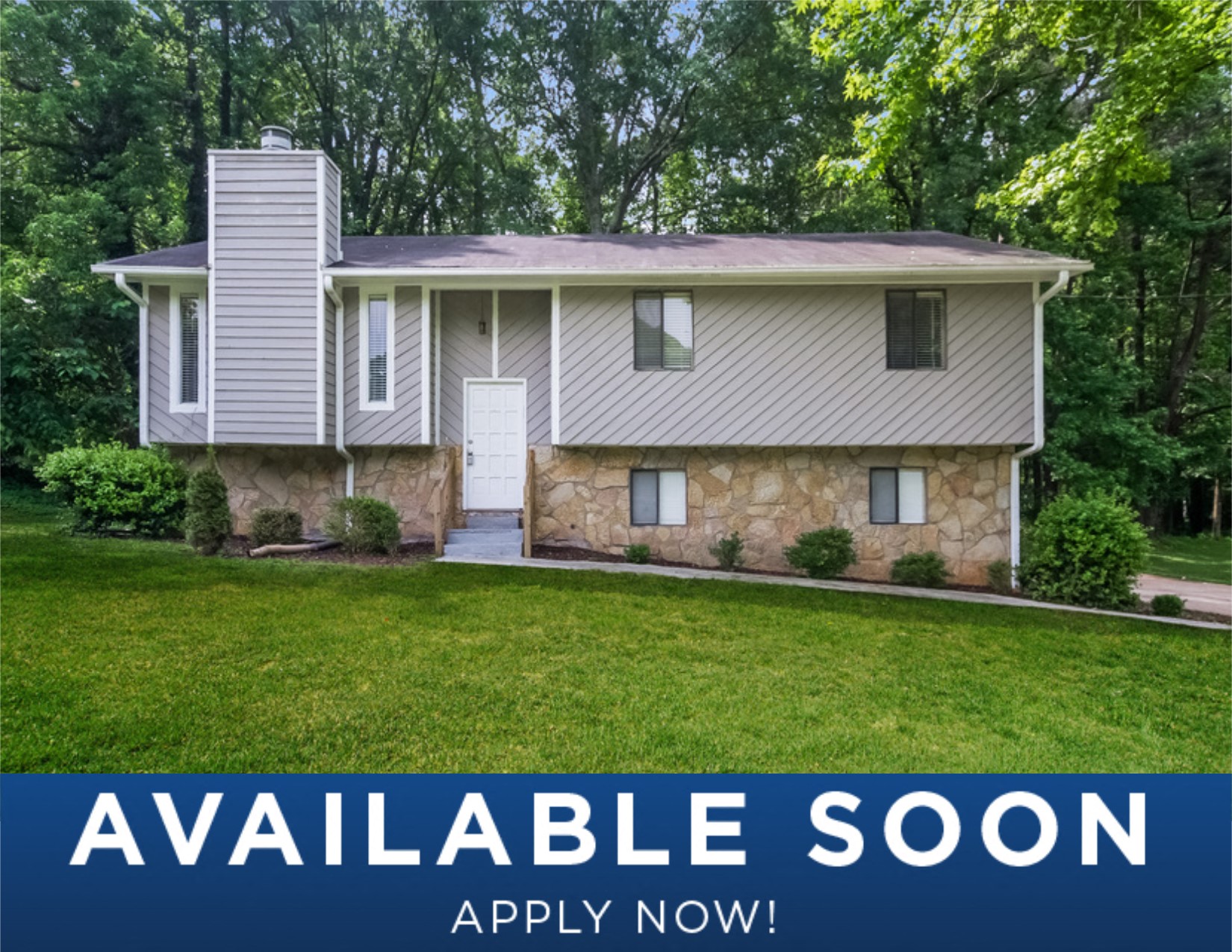 a white and stone house with a green lawn and trees