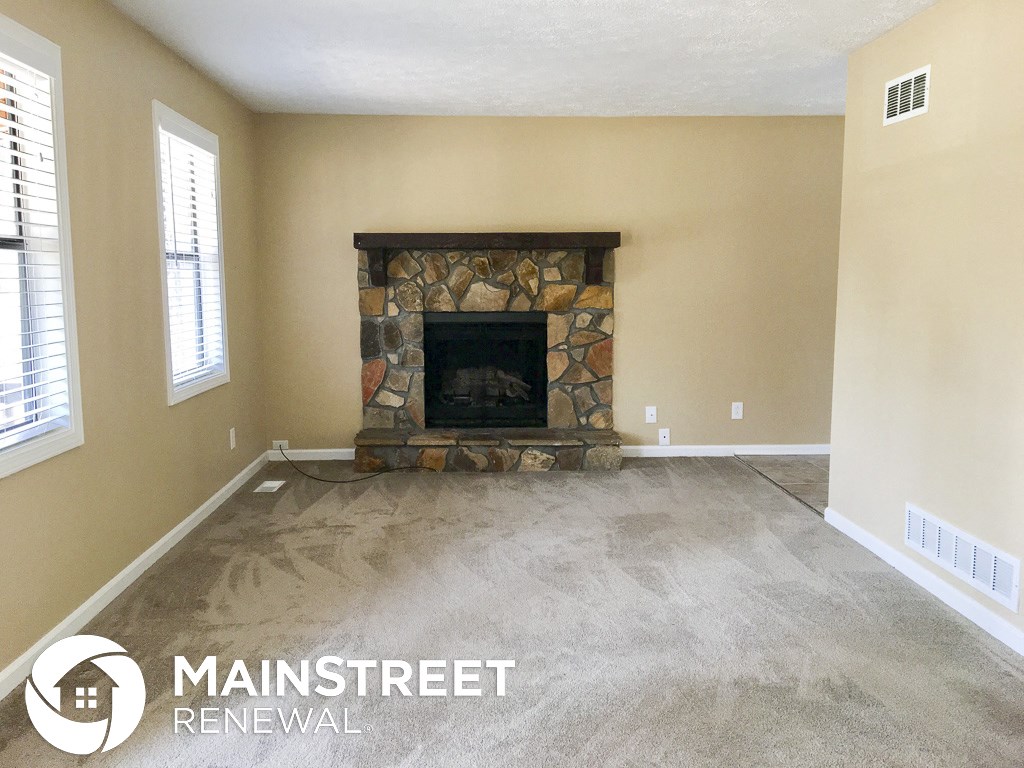 a living room with a fireplace and a carpeted floor