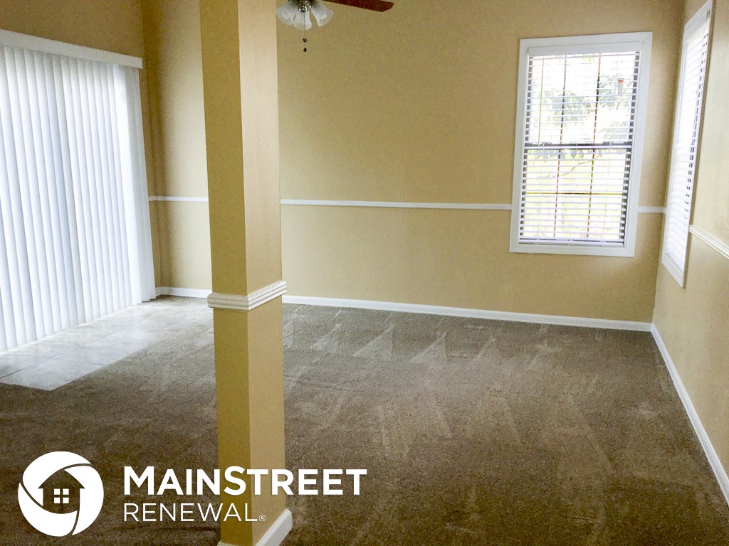 a living room with a carpeted floor and a ceiling fan