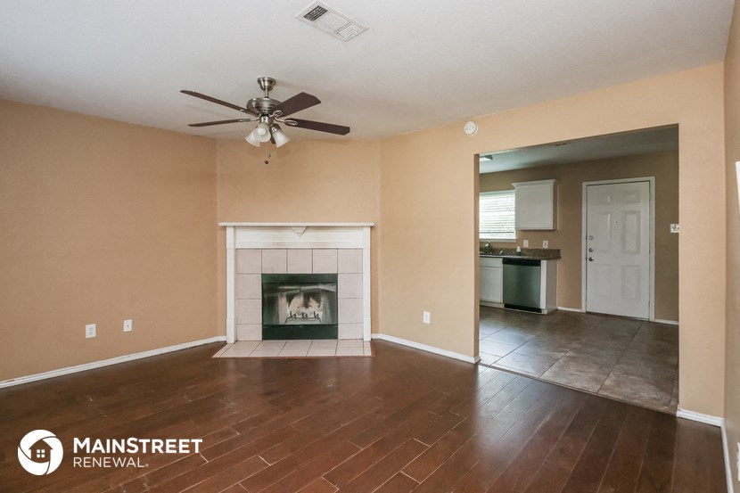 an empty living room with a fireplace and a ceiling fan