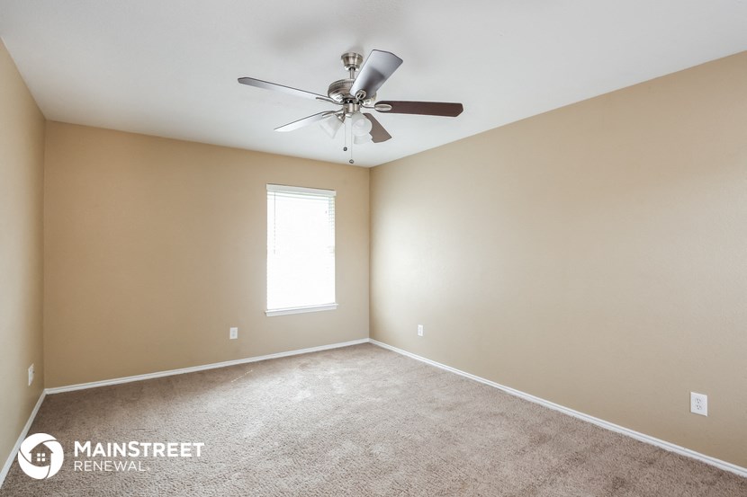 the master bedroom has a carpeted floor and a ceiling fan