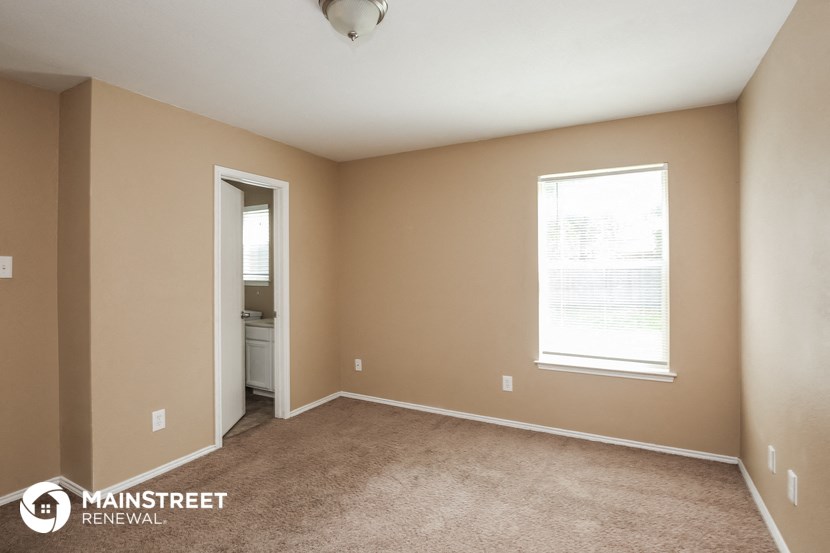 a bedroom with a carpeted floor and a door to a bathroom