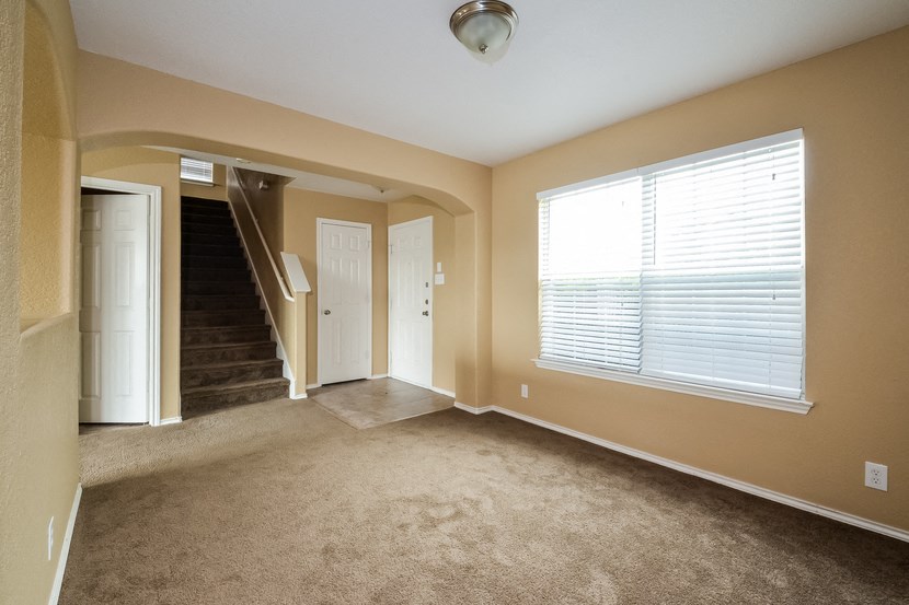 an empty living room with a large window and carpet