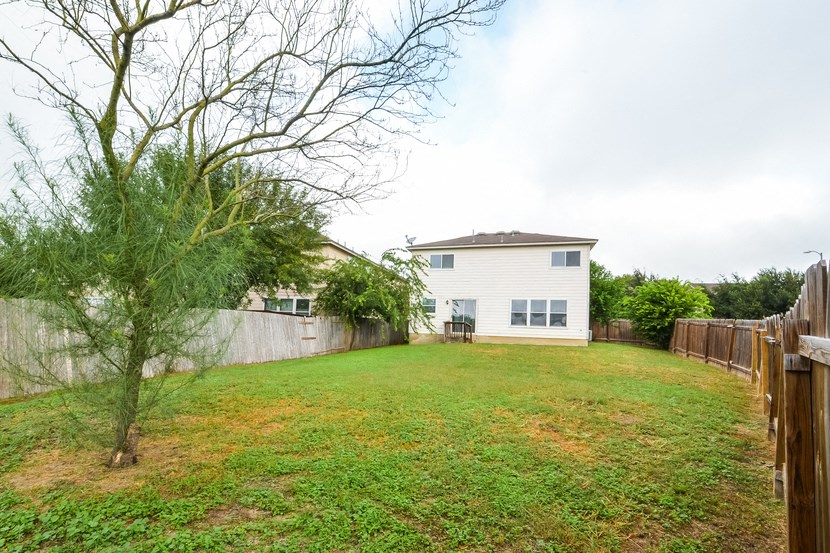the back yard of a house with a yard and a fence