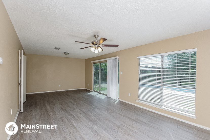 an empty living room with a ceiling fan and a large window