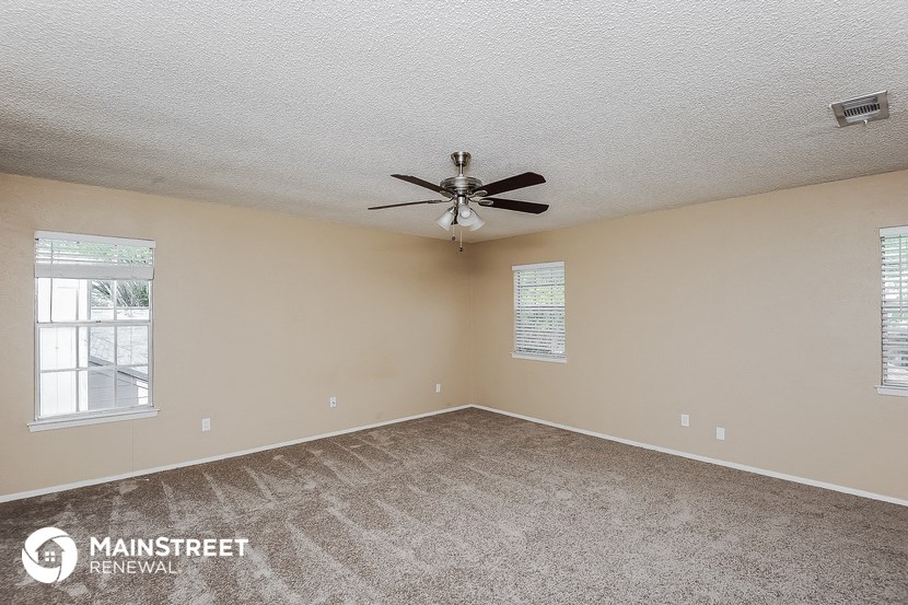 the spacious living room with carpeting and a ceiling fan