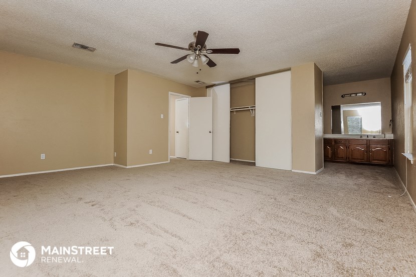 an empty living room with carpet and a ceiling fan