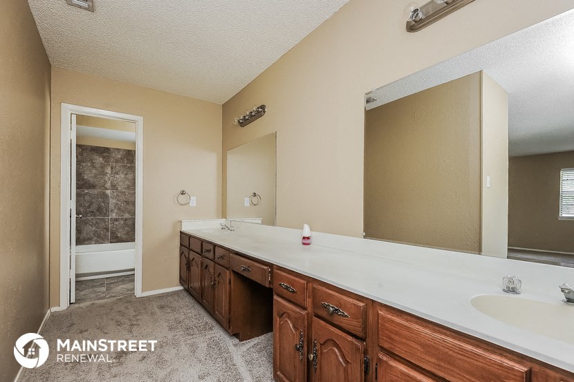 the master bathroom has a large vanity and a large mirror