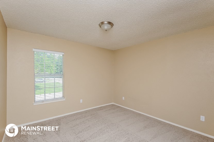 the spacious living room of an empty house with a window