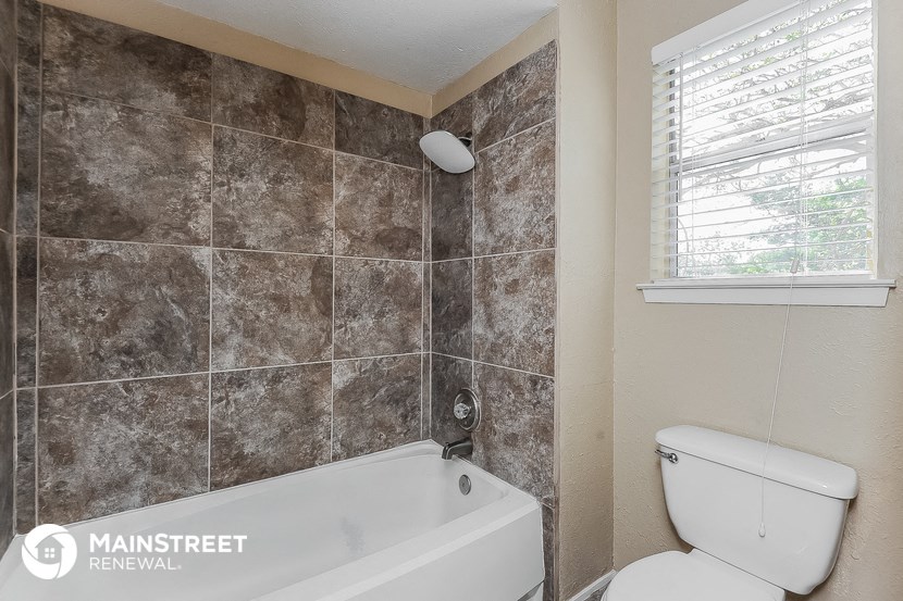 a bathroom with a tub and a toilet and a window