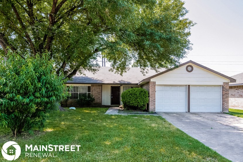 a small brick house with a garage and a tree
