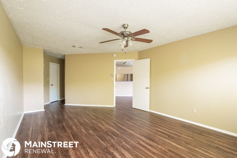 an empty living room with a ceiling fan and wood floors