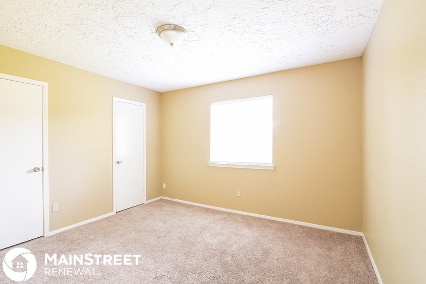 a bedroom with a carpeted floor and a door and a window