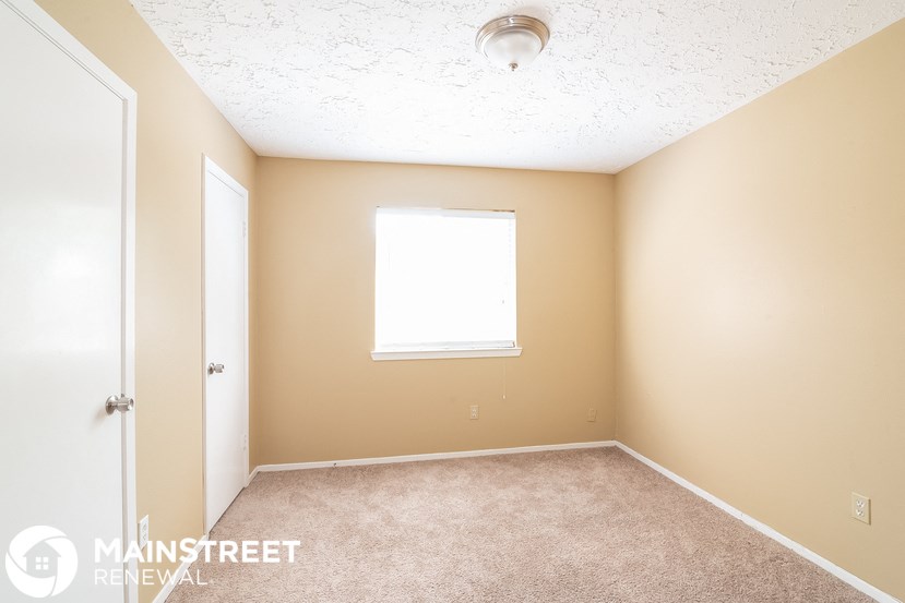 a bedroom with a carpeted floor and a window