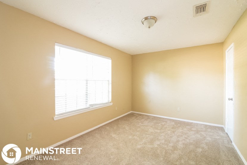 a bedroom with a large window and a carpeted floor