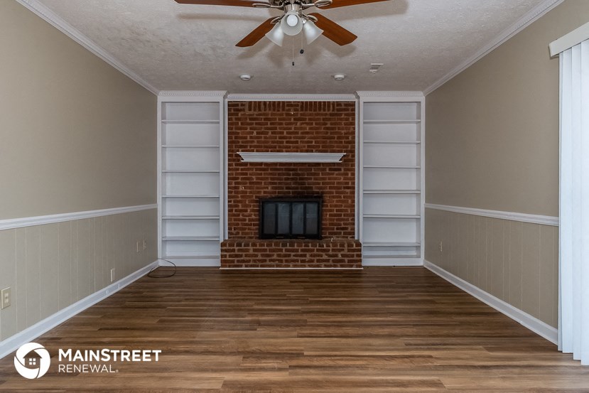 a living room with a brick fireplace and wooden floors
