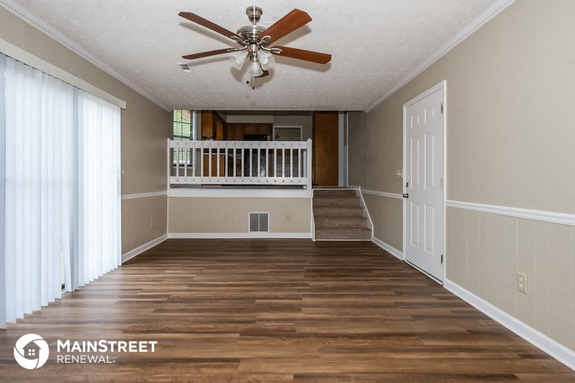 an empty living room with a staircase and a ceiling fan
