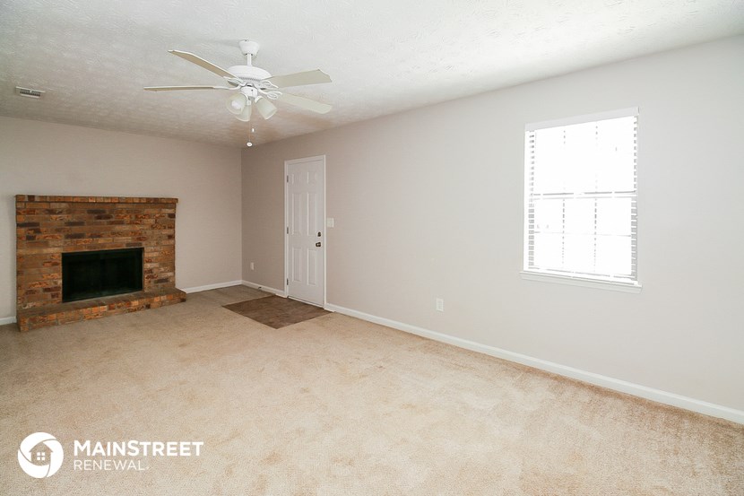 a living room with a fireplace and a ceiling fan
