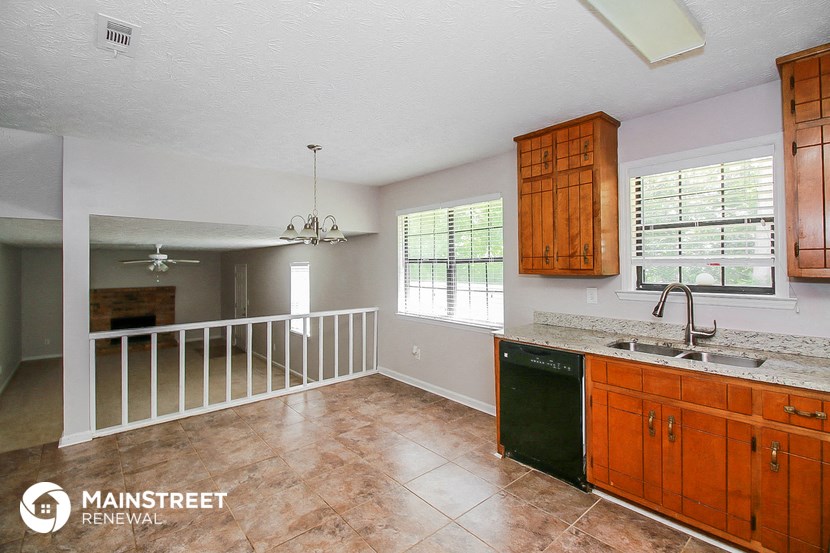 the kitchen and living room of a home with wood cabinets and a railing