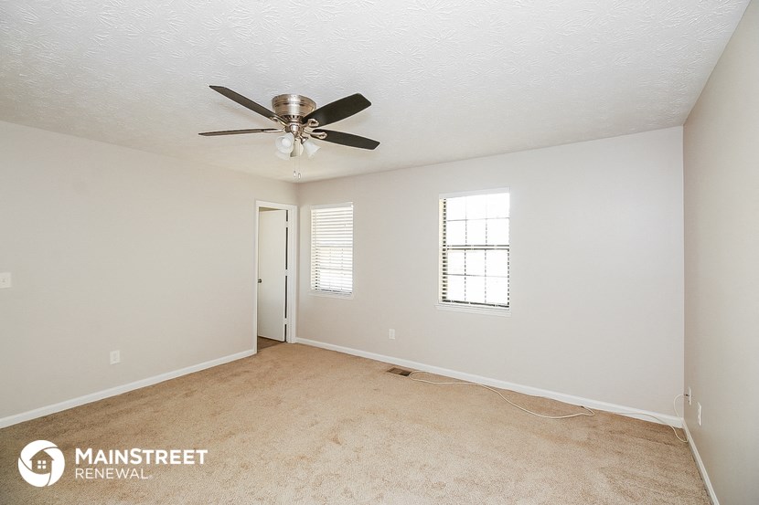 a bedroom with a ceiling fan and a carpeted floor