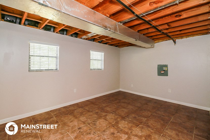 the living room of a home with tile flooring and a ceiling with exposed beams