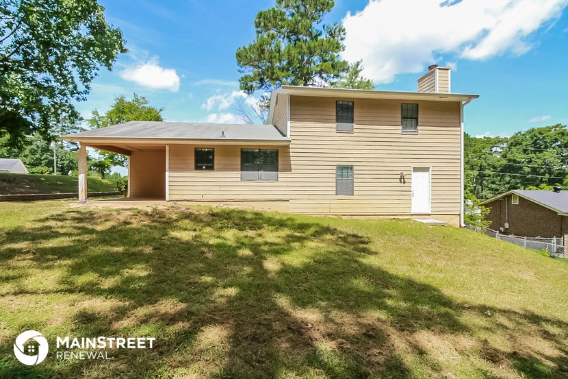 the front of a house with a lawn and a tree