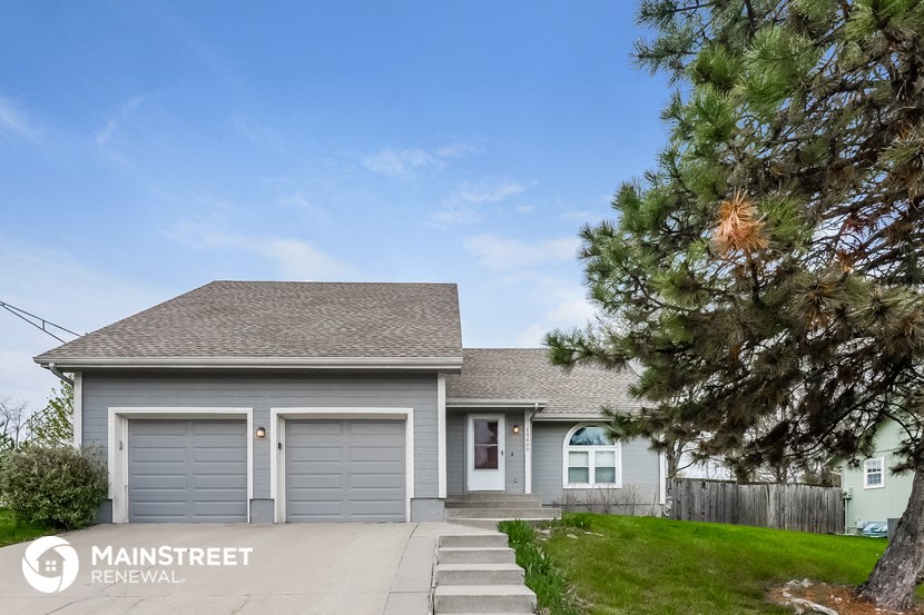 a small gray house with two garage doors