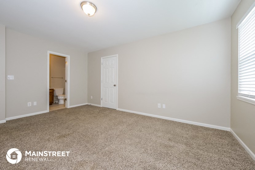 a spacious living room with carpet and a door to the bathroom