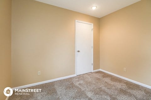 the living room of a new home with carpet and a white door