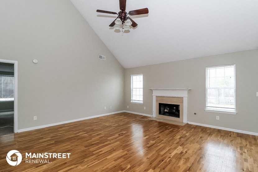 the living room with wood floors and a fireplace