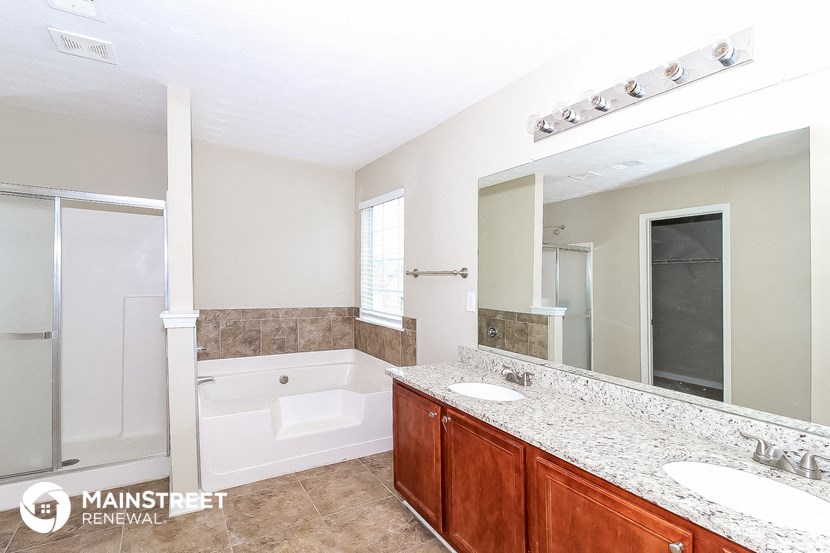 a bathroom with two sinks and a tub and a large mirror