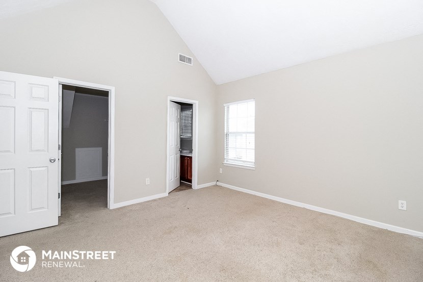 a bedroom with a carpeted floor and a door to a closet