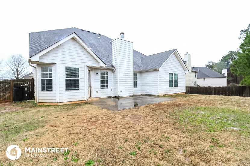 the back of a white house with a yard and a fence