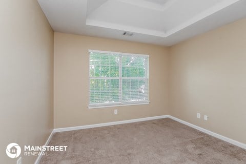 the living room of a new home with carpet and a window