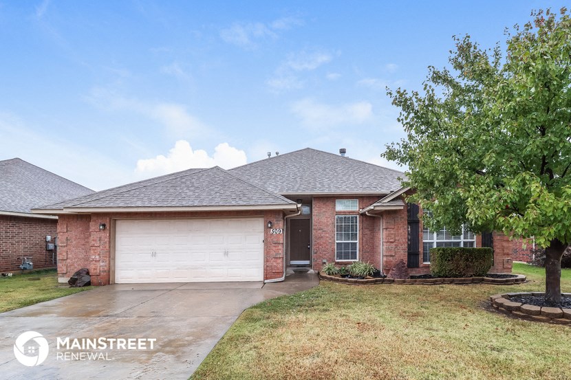 a brick house with a garage and a tree