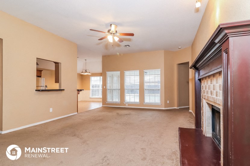 an empty living room with a fireplace and a ceiling fan