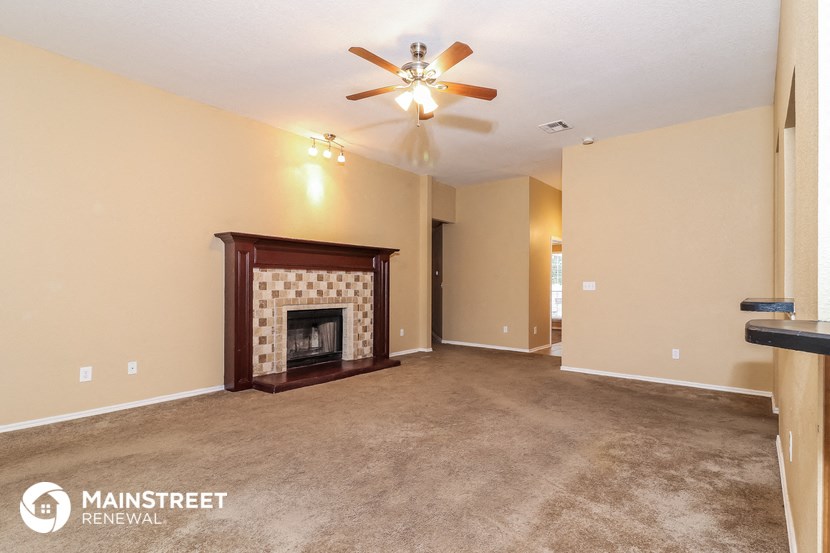 a living room with a fireplace and a ceiling fan