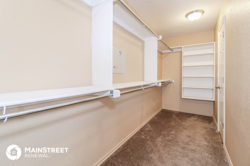 a walk in closet with white shelves and a carpeted floor