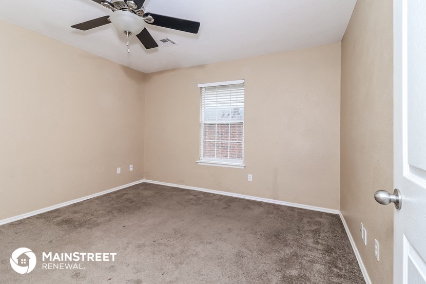 an empty room with a ceiling fan and a window