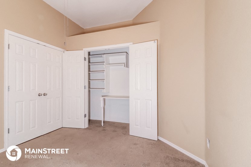 a bedroom with a closet and a desk with a chair in it