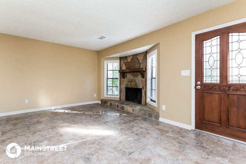 an empty living room with a fireplace and a wooden door
