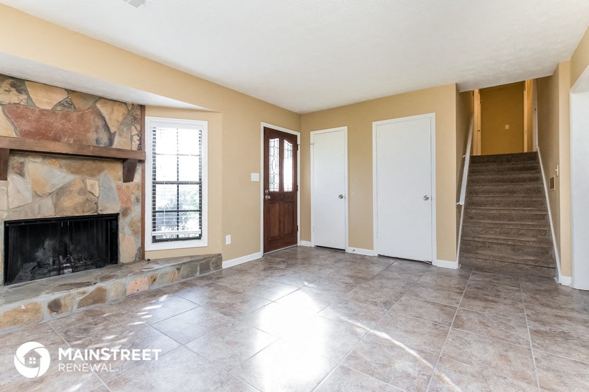 an empty living room with a fireplace and a staircase